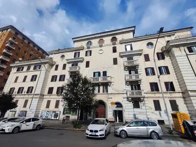 two cars parked in front of a large building at Portami a Roma in Rome