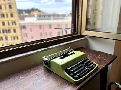 a green typewriter sitting on a table next to a window at La Casa del giornalista - ItalyHolidayHouse in Rome