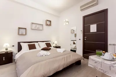 a white bed in a room with a table at Relais 155 Guest House in Rome