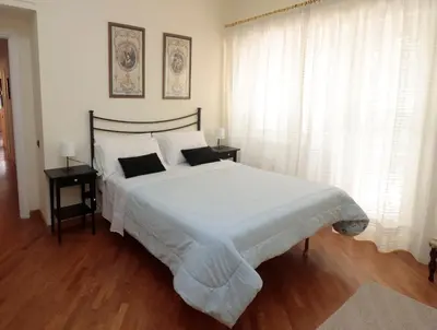 a bedroom with a large white bed with white curtains at Luminoso e accogliente appartamento con giardino - Battistini in Rome