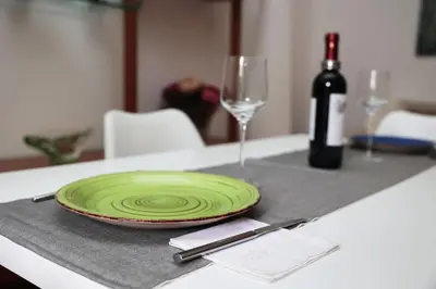a green plate on a table with a bottle of wine at Luminoso e accogliente appartamento con giardino - Battistini in Rome