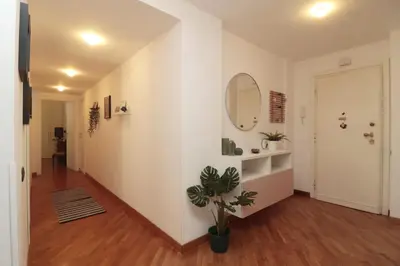 a hallway with white walls and a mirror and a plant at Luminoso e accogliente appartamento con giardino - Battistini in Rome