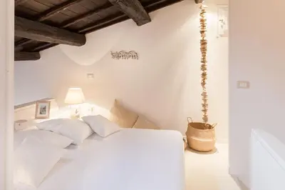 a bedroom with white walls and a bed with white pillows at Endless beauty - Charming attic in the heart of Rome in Rome