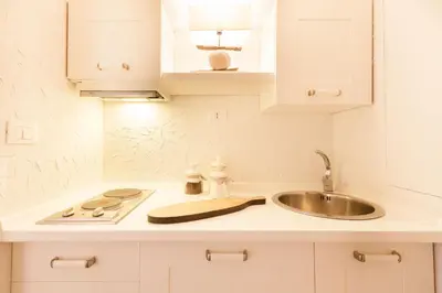 a white kitchen with a sink and a counter top at Endless beauty - Charming attic in the heart of Rome in Rome
