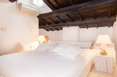 a white bed in a room with two lamps at Endless beauty - Charming attic in the heart of Rome in Rome
