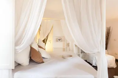 a white bed with white curtains in a bedroom at Endless beauty - Charming attic in the heart of Rome in Rome