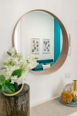 a mirror over a table with a vase with flowers at Parisi apt in Rome