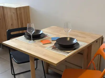 a wooden table with two glasses and two plates on it at San Giovanni Apartment in Rome