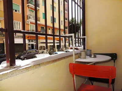 a red chair sitting in front of a table and a window at Kalu apartment in Rome