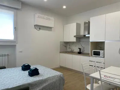a kitchen with white cabinets and a table and chairs at [COLOSSEUM] Latin Romans Apartments in Rome