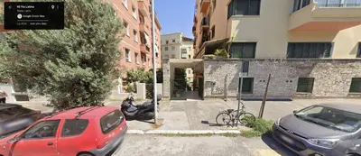 a red car parked in a parking lot next to buildings at [COLOSSEUM] Latin Romans Apartments in Rome