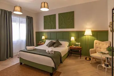 a bedroom with a large bed and a chair at Ary's Vatican Holiday Home in Rome