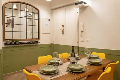 a dining room with a wooden table and yellow chairs at Ary's Vatican Holiday Home in Rome