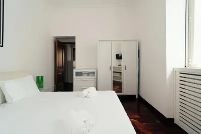 a bedroom with a white bed and a refrigerator at Art House Vaticano Apartment in Rome