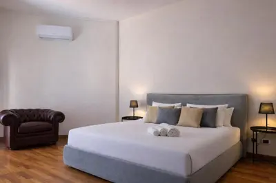 a bedroom with a large white bed and a chair at èROMA - SAN PAOLO BASILICA Apartment in Rome