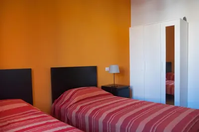 two beds in a room with orange walls at Welcome Friends in Rome