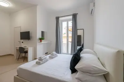 a white bedroom with a bed and a desk at San Giovanni Boutique Suites in Rome