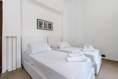 two beds in a room with white walls at San Giovanni Boutique Suites in Rome