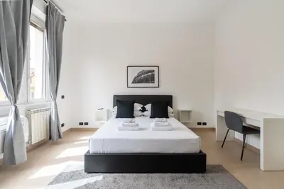 a white bedroom with a bed and a desk at San Giovanni Boutique Suites in Rome