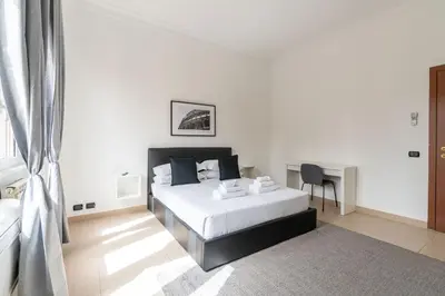 a white bedroom with a bed and a desk at San Giovanni Boutique Suites in Rome