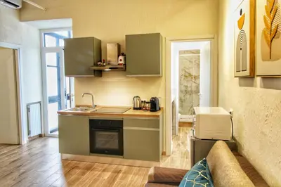 a kitchen with green cabinets and a couch in a room at Lovely 2 Bedroom apartment by YourHost in Rome