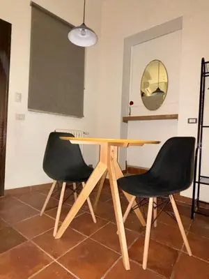 a wooden table with two black chairs and a mirror at Flaminia's House San Pietro Station in Rome