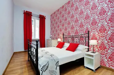 a bedroom with a bed with a red wall at Cozy Tritone - My Extra Home in Rome