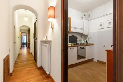 a kitchen with white cabinets and a wooden floor at Monti Charming Amphora Apartment in Rome