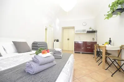 a room with a bed with towels and a kitchen at Prati House in Rome