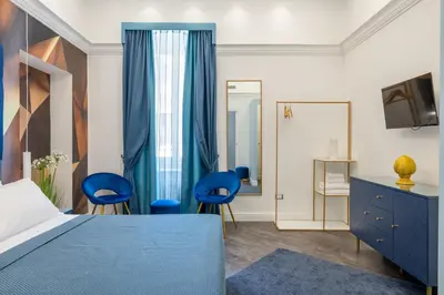 a bedroom with a bed and two blue chairs at Antiqua Domus in Rome