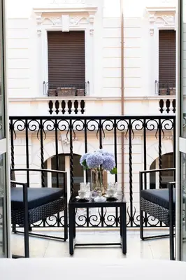 a balcony with two chairs and a table with flowers at Belli Boutique Guest House in Rome