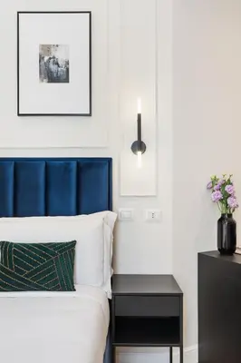 a bed with a blue headboard and a black nightstand at Belli Boutique Guest House in Rome