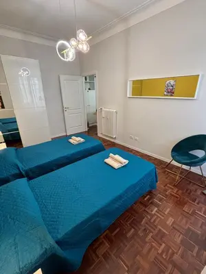 a bedroom with two blue beds and a chair at La Casa di Rosa , Elegante Appartamento a Corso Trieste, Metro B in Rome