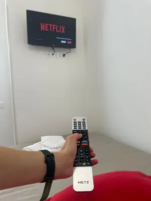 a person holding a remote control in front of a tv at Trastevere Station Sweet Rest in Rome