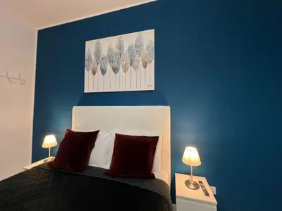 a bedroom with a blue wall and a bed with red pillows at affittacamere appia nuova 639 in Rome