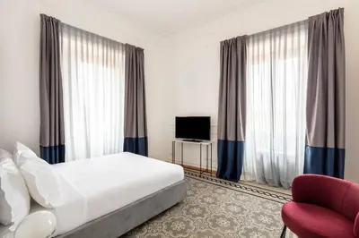 a bedroom with a bed and a chair and a television at SJR Luxury Apartment Trevi Fountain in Rome