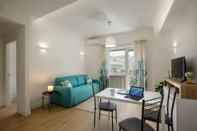 a living room with a blue couch and a table with a laptop at Pio Vatican Flat in Rome