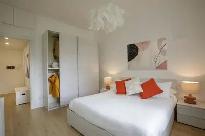 a white bedroom with a white bed and orange pillows at Pio Vatican Flat in Rome