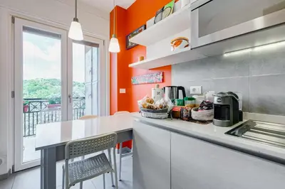 a kitchen with orange walls and a counter with chairs at Valle Aurelia Vatican Home - Beutiful View & Wi-Fi in Rome