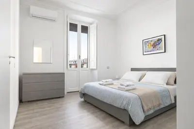 a white bedroom with a bed and a window at Central Rome 2BR Walk to Vatican & Piazza Navona in Rome