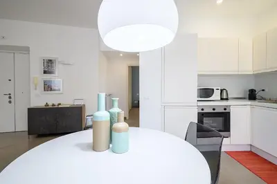 a white kitchen with a white dining room table and a kitchen with white cabinets at D'Aquino Apartment St. Peter's in Rome