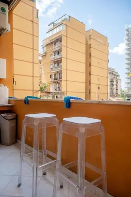 two stools on a balcony with a view of buildings at Cerroni's Corner in Rome