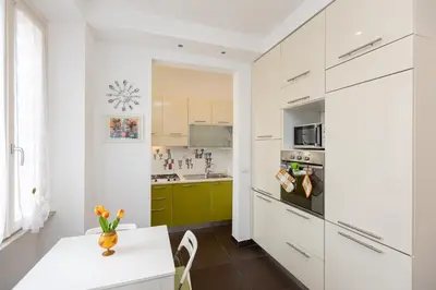 a kitchen with white cabinets and a white table at Tasso by Rental in Rome in Rome