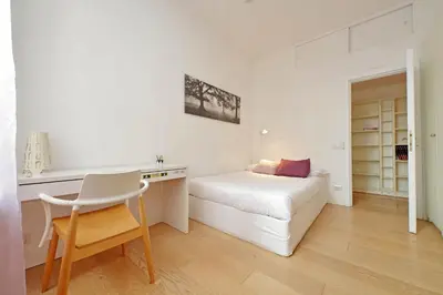a white bedroom with a bed and a desk at San Pietro Al Vaticano by Halldis in Rome