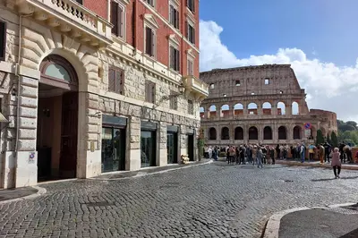 a group of people walking down a street in front of a building at Colosseo Way in Rome