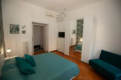 a bedroom with a green bed and a couch at Three sisters- La casa nel Cuore di Roma in Rome