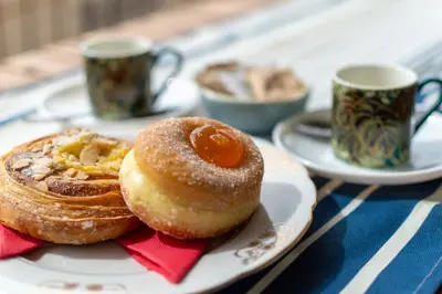 two donuts on a plate on a table with two cups at TESTACCIO XIX-XXV Bed & Breakfast in Rome