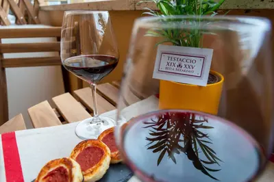 a glass of red wine next to a plate of food at TESTACCIO XIX-XXV Bed & Breakfast in Rome