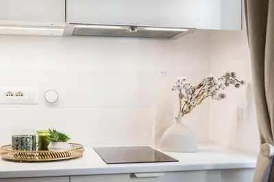 a white vase with flowers on a kitchen counter at Cantoni 4B - Studio at Colosseum in Rome