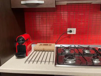 a kitchen counter with a stove and a red tiled wall at Aniene GH in Rome